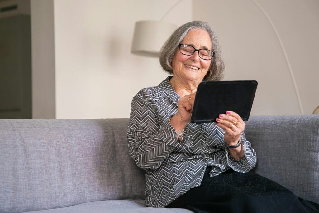 Frau ab 50 lächelt beim Entdecken neuer Bekanntschaften auf dem Tablet – Neuanfang nach der Scheidung