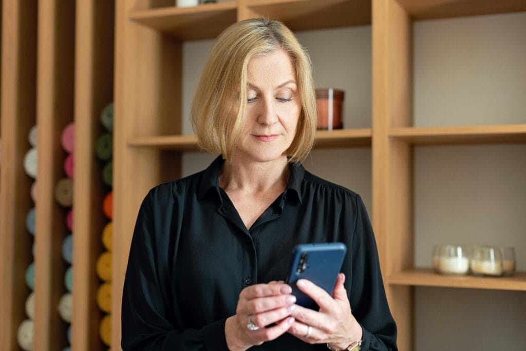 Frau ab 55 schaut konzentriert auf ihr Smartphone – überlegt wann der richtige Moment für ein erstes Treffen ist