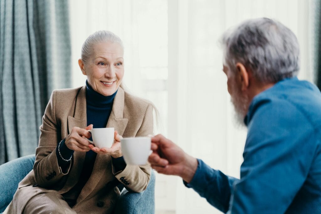Frau ab 60 lächelt offen beim ersten Treffen mit Kaffee – der richtige Moment ist gekommen, vom Schreiben zur Begegnung